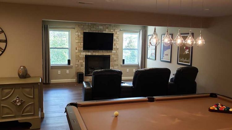 Finished basement accent wall with fireplace & tv.